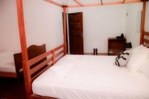 - une chambre avec un grand lit blanc dans l'établissement Rainforest Chalets - Rainforest Tours,Pool And Ac, à Deniyaya