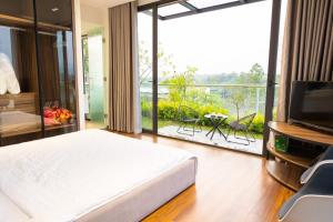 - une chambre avec un lit, une télévision et un balcon dans l'établissement Villa & Resort Đại Lải - 3, à Phúc Yên