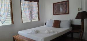 a bedroom with a bed with two towels on it at SUMMER HOMES BEACH RESORT in Port Barton