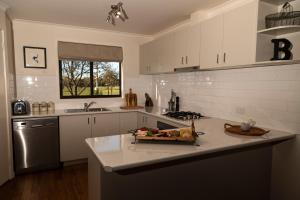 a kitchen with white cabinets and a counter top at Butmaroo Station in Bungendore