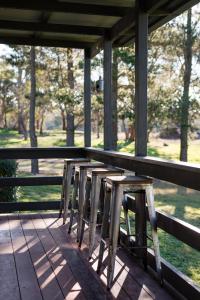 a row of stools sitting on a porch with trees at Butmaroo Station in Bungendore