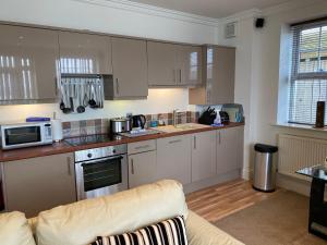 a kitchen with white cabinets and a couch at Southover Beach in Woolacombe