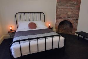 een slaapkamer met een bed en een stenen open haard bij Heritage Cottage in the heart of Bendigo in Bendigo
