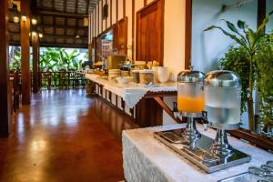 a restaurant with a row of tables with orange juice at Villa Chitdara in Luang Prabang
