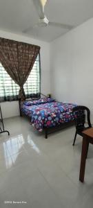 a bedroom with a bed and a chair and a window at Homestay Indera kayangan in Kangar