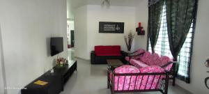 a living room with a pink couch and a tv at Homestay Indera kayangan in Kangar