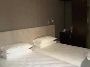 een bed met witte lakens en kussens in een kamer bij Bergliot Guest House in Edenvale