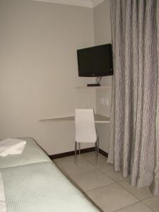 a bedroom with a bed and a tv and a chair at Bergliot Guest House in Edenvale