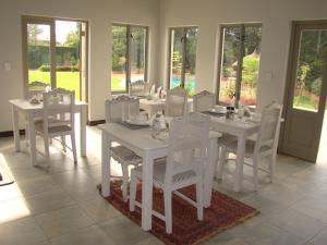 a white dining room with white tables and white chairs at Bergliot Guest House in Edenvale