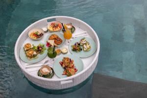 Giri Bhagawan Villas & Spa في نوسا دوا: طاولة دائرية مع أطباق من الطعام والمشروبات