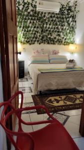 a bedroom with a bed and a red chair at Casa Luz Mi casa tu casa in Sabanitas