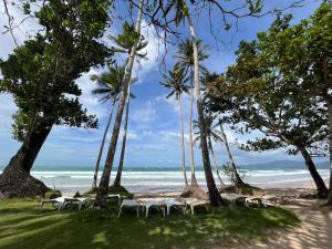 a beach with white tables and palm trees and the ocean at Hill Myna Beach Cottages in Sabang