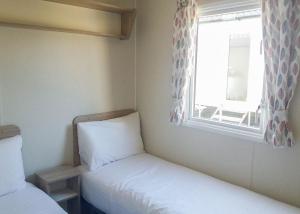 a small room with two beds and a window at St Cyrus Park in Montrose