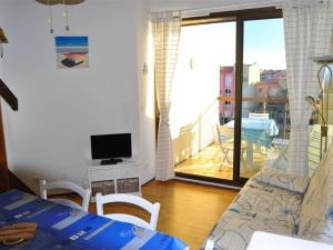 een woonkamer met een bank, een televisie en een balkon bij Appartement Port Barcarès, 3 pièces, 6 personnes - FR-1-431-15 in Le Barcarès