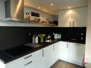 una cocina con armarios blancos y encimeras negras en Holiday home Sunset en Noordwijkerhout