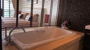 a bath tub in a bathroom with a dog looking out the window at Phupha Rayong by gift in Klaeng