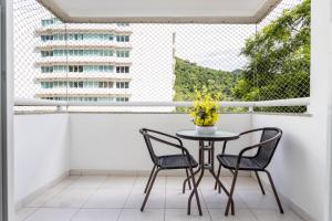 einen Tisch und zwei Stühle auf einem Balkon mit Fenster in der Unterkunft 3 QUARTOS em Condominio com PISCINA, ESTACIONAMENTO e Portaria 24h a 300m do Centro de Convenções RIOCENTRO in Rio de Janeiro