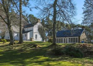 Biały dom z drzewami przed nim w obiekcie Gledfield Highland Estate w mieście Culrain