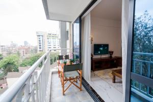a balcony with a television and a table and a chair at Lux Suites Sandalwood Furnished Apartments in Nairobi