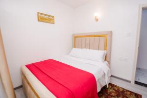 a bedroom with a bed with a red blanket on it at Lux Suites Sandalwood Furnished Apartments in Nairobi