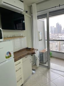 eine Küche mit weißen Schränken und einem großen Fenster in der Unterkunft Studio with Sun Terrace - 1 in Bat Yam