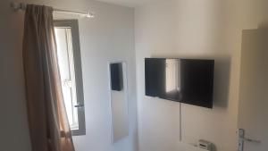 Zimmer mit einem TV an der Wand und einem Fenster in der Unterkunft Appartement T2 avec vue - Port Leucate - 4 personnes in Leucate