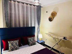 een slaapkamer met een bed met een blauw hoofdeinde en een raam bij Hyfram Homes - Peaceful, Quiet, very fast WI-FI in Kampala