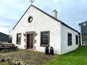 a white building with a picnic table in front of it at Beautiful Rural 3BR Cottage with Stunning Views in Auldgirth