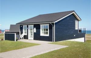 a black house with a white door and a chair at Holiday Home Bagenkop With Fireplace 05 in Bagenkop