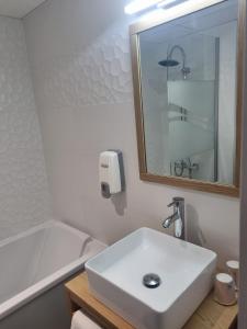 a white bathroom with a sink and a bath tub at Hotel Cantosorgue in L'Isle-sur-la-Sorgue