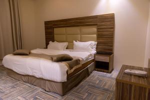 a bedroom with a large bed with a wooden headboard at منــازل الماسة للشقق المخدومة عنيزة in Unayzah