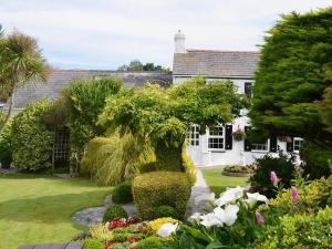 a white house with a garden with flowers at The Haven in Crantock