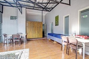 1 dormitorio con mesa, sillas y 1 cama en Capital O 92250 Hall & Guesthouse Kowapi Syariah, en Purwokerto