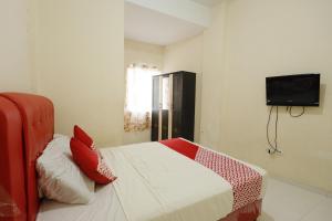 a bedroom with a bed with red pillows and a tv at OYO 92261 Aulia Homestay Syariah in Bagam