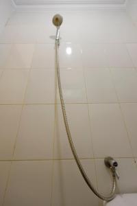 a shower with a hose on a white tiled wall at OYO 92261 Aulia Homestay Syariah in Bagam
