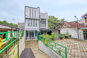 una vista exterior de una casa con una valla verde en Capital O 92250 Hall & Guesthouse Kowapi Syariah, en Purwokerto