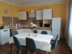 kuchnia z białym stołem z krzesłami i białą lodówką w obiekcie Villa-Gallant w Popradzie