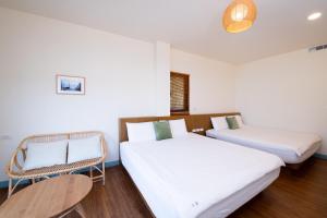 two beds in a room with white walls and wooden floors at Lixia Hostel in Xiaoliuqiu