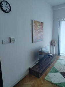 RDR Homestay@Emira Residence في شاه عالم: غرفة معيشة فيها تلفزيون وساعة على الحائط