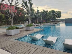 - une piscine avec 2 chaises blanches dans l'eau dans l'établissement RDR Homestay@Emira Residence, à Shah Alam