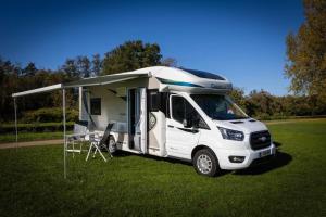 Ein weißer Truck parkt auf einem Feld mit einem Camper. in der Unterkunft Pop Up Camping Tomorrow's Paradise in Schelle