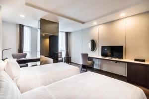 a hotel room with two beds and a flat screen tv at SureStay Plus Hotel by Best Western Sukhumvit 2 in Bangkok