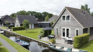 een huis met een terras naast een rivier bij De Sloothaak in Giethoorn