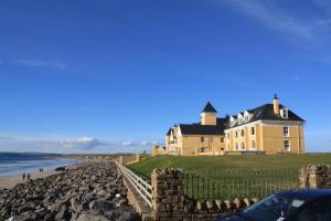 une grande maison jaune sur la rive d'une plage dans l'établissement Sandhouse Hotel, à Rossnowlagh