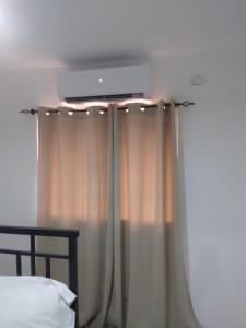 um quarto com uma cama e uma janela com cortinas em Precioso apartamento, residencial Carmen Renata III,Cerca Embajada Américana em El Seis