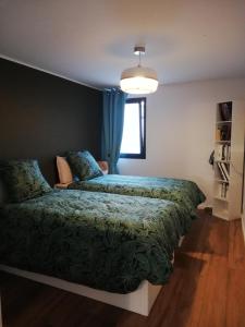 um quarto com uma cama com um edredão verde e uma janela em Le 26 em Ruffec