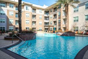 - une grande piscine dans un complexe d'appartements avec des palmiers dans l'établissement PackHouse 2, à Houston