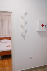 a white room with a bed and a red cross on the wall at Apartman PETRA in Trogir