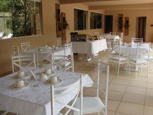 a dining room with white tables and white chairs at Pousada Lava-Pés in Itambé do Mato Dentro