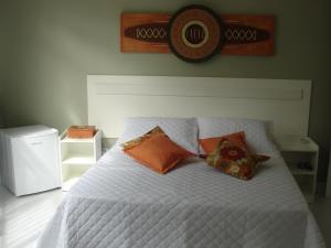 a bedroom with a white bed with orange pillows at Pousada Lava-Pés in Itambé do Mato Dentro